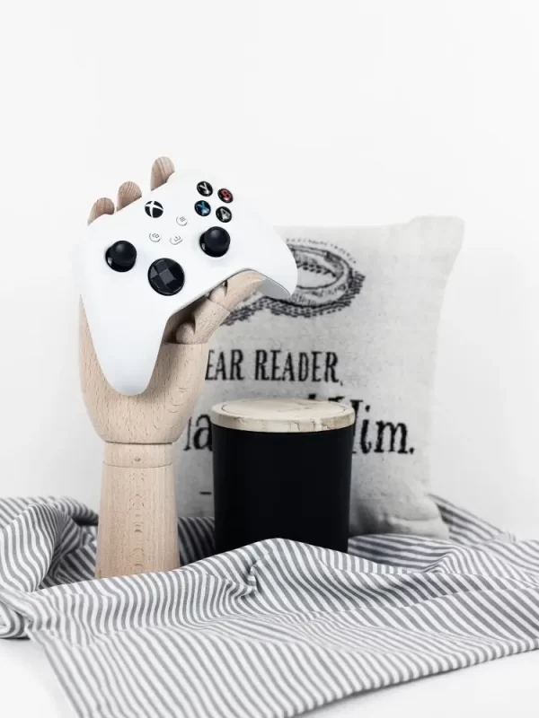 This is a geeky home decor photo with a video game controller, a pillow, and a candle.