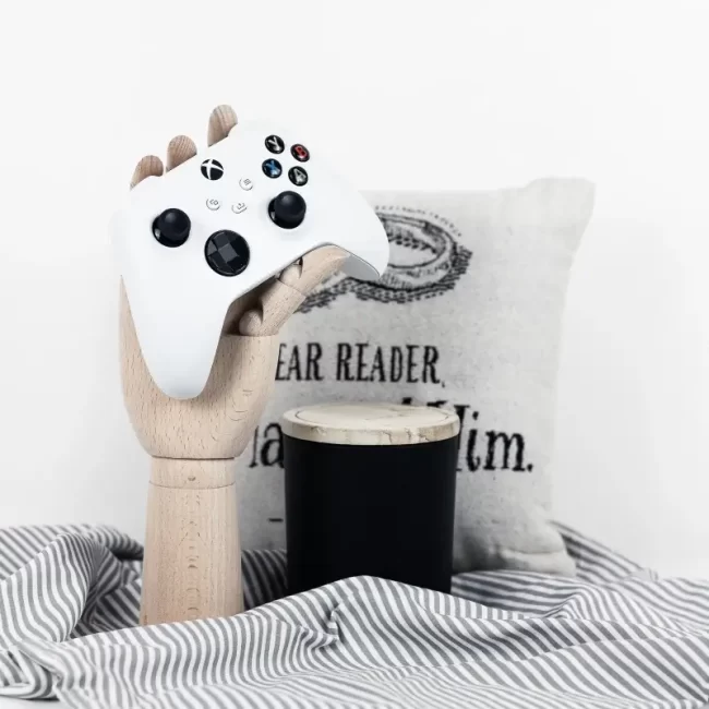 This is a geeky home decor photo with a video game controller, a pillow, and a candle.