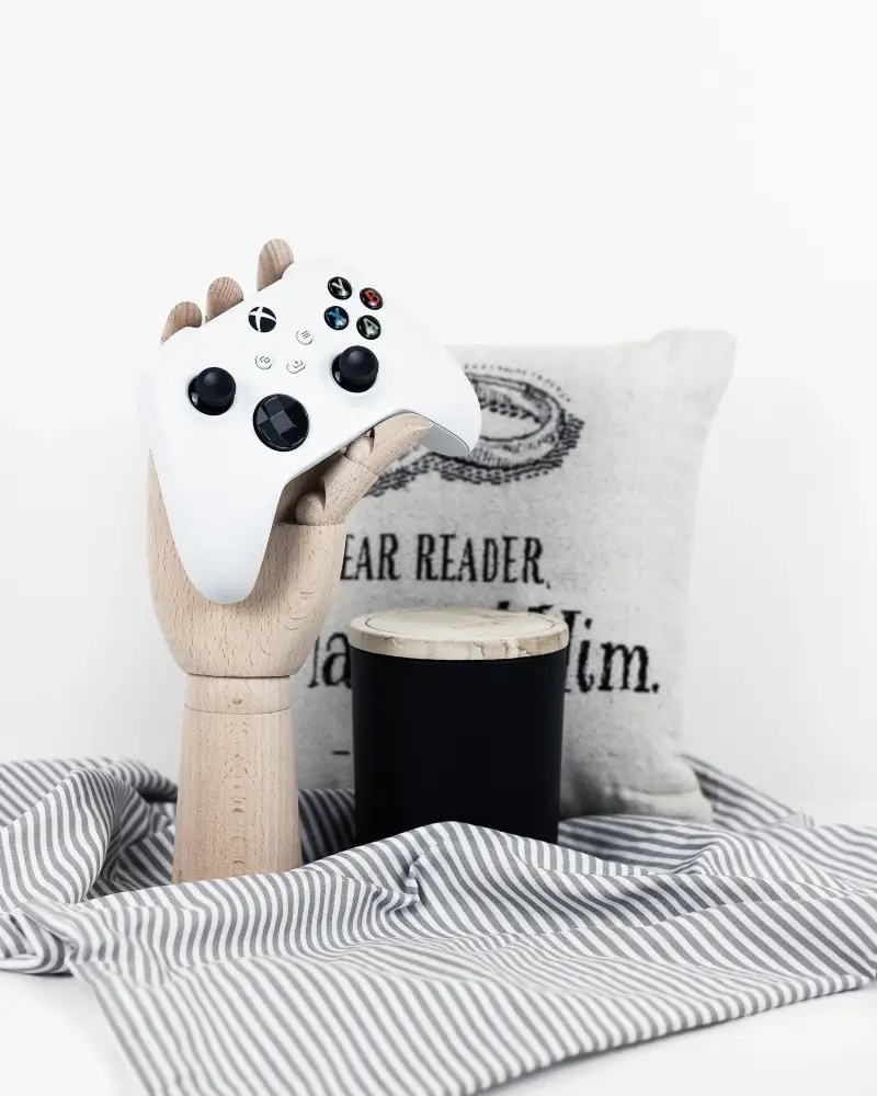 This is a geeky home decor photo with a video game controller, a pillow, and a candle.