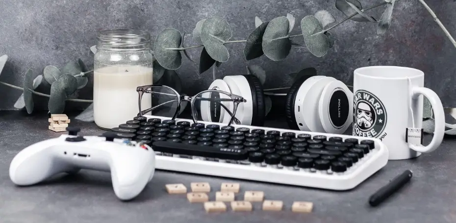 This image has a white keyboard, white controller, star wars stormtropper mug, white headphones, glasses, a white candle, and scrabble letters that spell you got this.