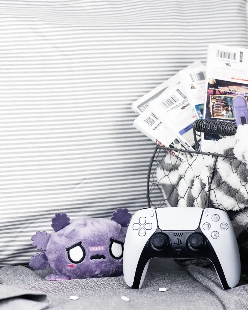 cozy games in a basket with a controller and a plushie to play when you're sick