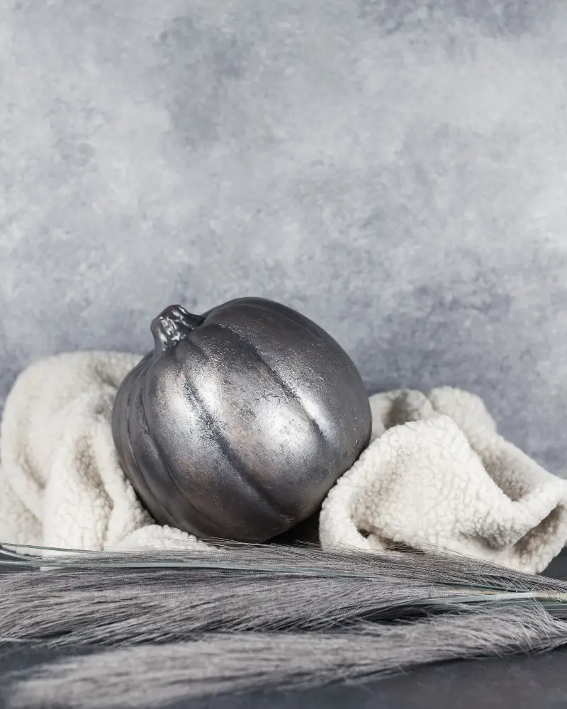 metal painted pumpkin on a blanket for fall home decor trends for 2023, this geeked out blog