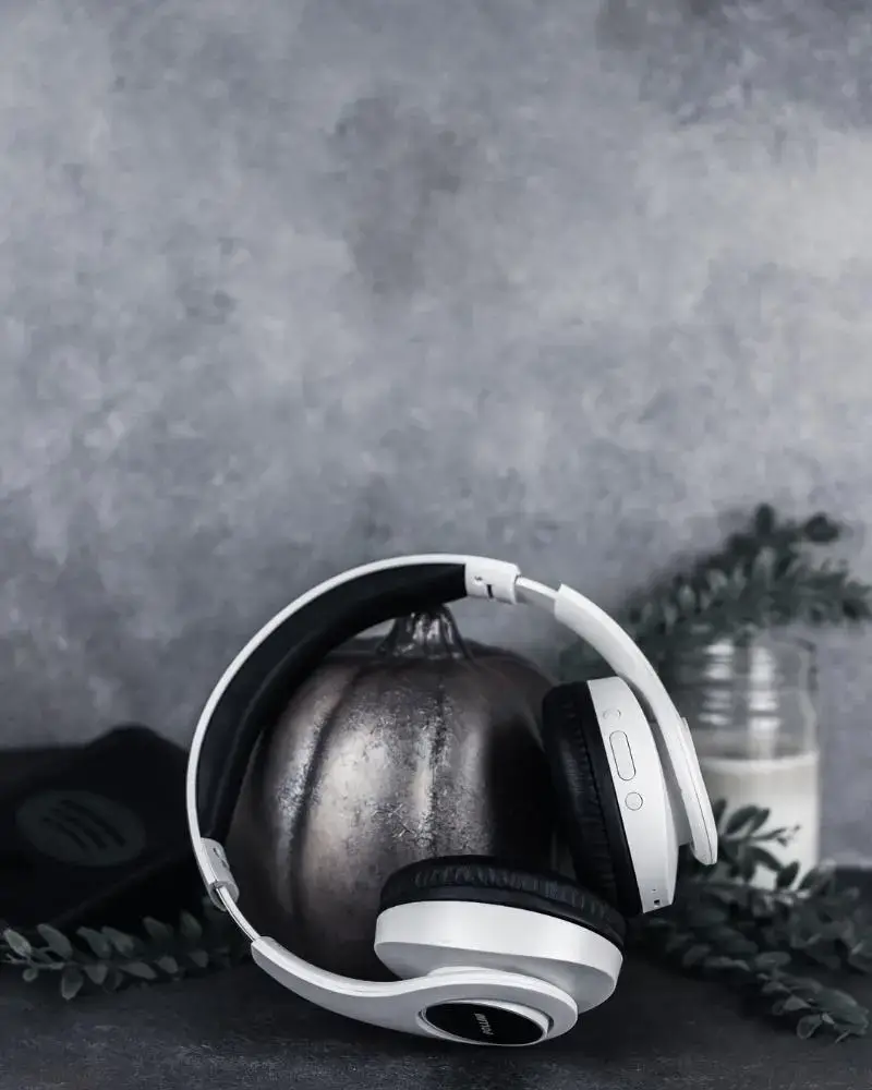 White headphones with industrial pumpkin, candle, and cell phone with Spotify logo